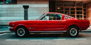 Red 67 Mustang sitting along the street.