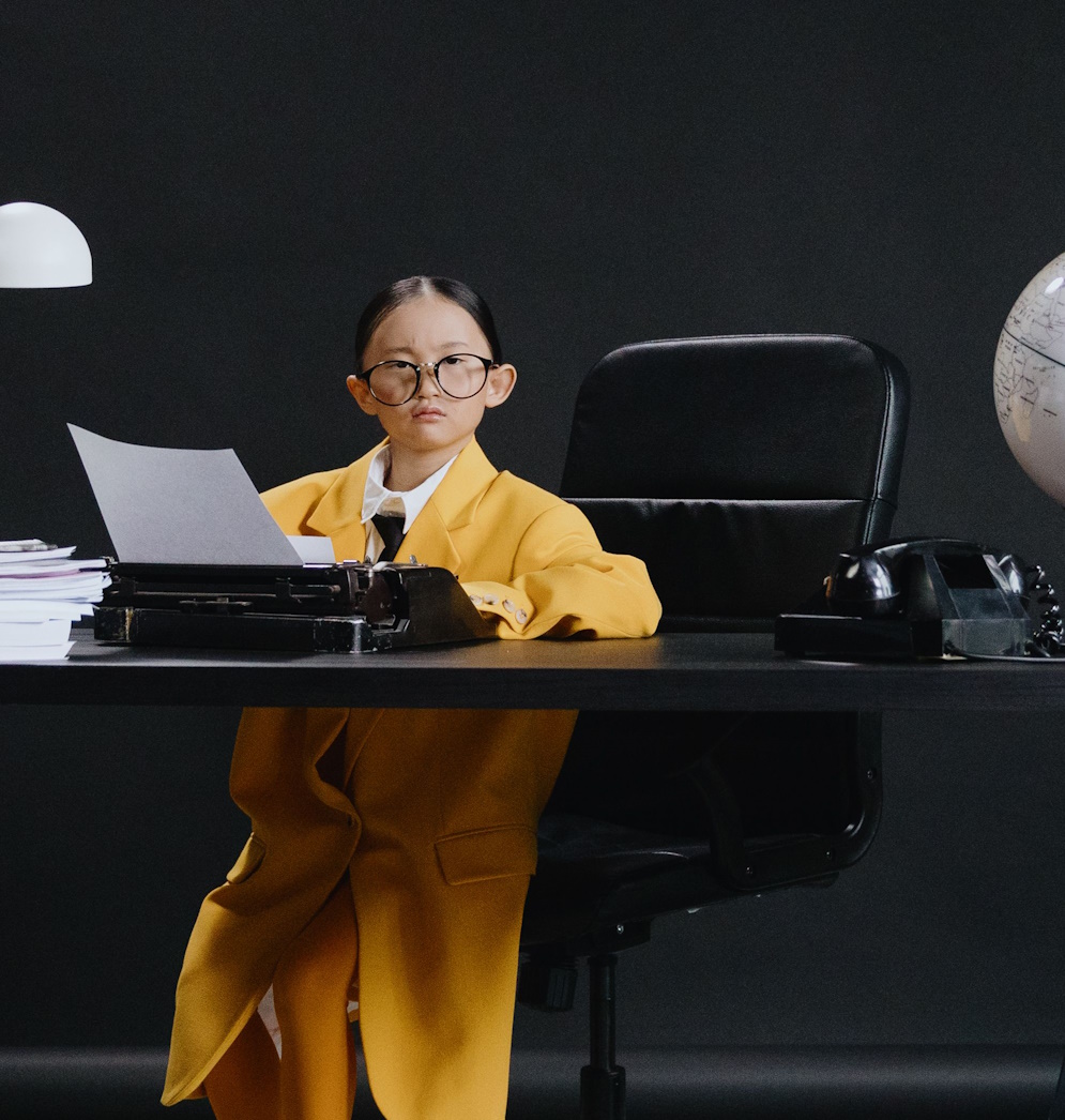 Pre--teen girl dressed in yellow sitting at an office desk